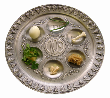 Passover seder plate with charoset, parsley, roasted bone, roasted egg and bitter herbs (maror)